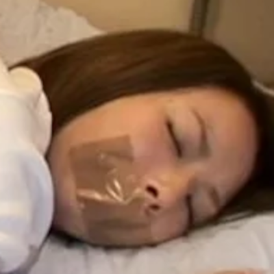 口を茶色のガムテープで封じられた女性の顔アップ